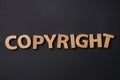 Word Copyright made of wooden letters on black background, flat lay. Plagiarism concept