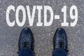 Word COVID-19 written on asphalt with shoes, concept background