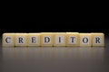 The word CREDITOR written on wooden cubes isolated on a black background