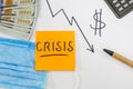 The word `crisis` on an orange sticker on the background of business charts, dollars and a calculator. View from above. The concep Royalty Free Stock Photo