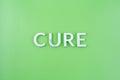 The word cure laid with thick aluminium letters on green background