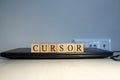 The word cursor is written. Computer and headset in the background. Royalty Free Stock Photo