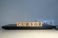 The word cursor is written. Computer and headset in the background. Royalty Free Stock Photo