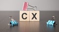 word cx with wood building blocks with paper clips