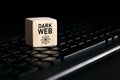 The word dark web on wooden cube with computer keyboard. Cyber crime and illegal outlets in cyberspace or internet technology