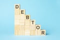 the word DEBTOR is written on a wooden cubes, concept
