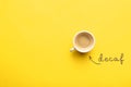 Word Decaf and cup of coffee on yellow background, top view. Space for text