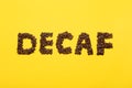 Word Decaf made of coffee beans on yellow background, flat lay