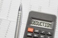 The word DEDUCTION is written on the digital display of the calculator lying on the financial statements  top view  tax concept Royalty Free Stock Photo