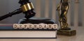 Word DEFENDANT composed of wooden dices. Wooden gavel and statue of Themis in the background