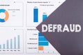 The word DEFRAUD is written on a gray background with diagrams and graphs Royalty Free Stock Photo