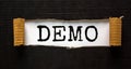 The word `demo` appearing behind torn black paper. Business concept