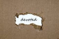 The word devoted appearing behind torn paper