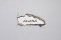 The word devoted appearing behind torn paper