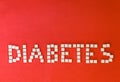 Word diabetes, healthcare concept, made of refined loaf sugar cubes on red backround