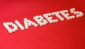 Word diabetes, healthcare concept, made of refined loaf sugar cubes on red backround