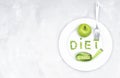 Word DIET made of garden peas on a large white plate with a fresh green apple, a soft tape measure and a fork on a concrete table Royalty Free Stock Photo