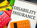 Word DISABILITY INSURANCE on notebook with calculator,pencil and push pins.Insurance concept.