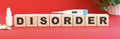 The word DISORDER is made of wooden cubes on a red background. Medical concept