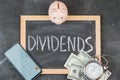 The word DIVIDENDS on a black chalk board in a frame, top view . Selective focus Royalty Free Stock Photo