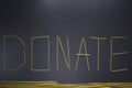 Word `donate` written with spaghetti on gray background, top view, copy space. Food supplies, donation on quarantine