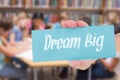 Dream big against cute pupils writing at desk in library Royalty Free Stock Photo