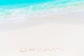 Word Dream handwritten on sandy beach with turquoise water