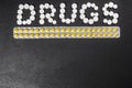 The word `drugs` is laid out of pills on a dark background with packets of pills Royalty Free Stock Photo