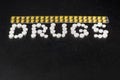 The word `drugs` is laid out of pills on a dark background with packets of pills Royalty Free Stock Photo