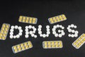 The word `drugs` is laid out of pills on a dark background with packets of pills Royalty Free Stock Photo