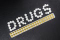 The word `drugs` is laid out of pills on a dark background with packets of pills Royalty Free Stock Photo