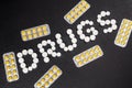 The word `drugs` is laid out of pills on a dark background with packets of pills Royalty Free Stock Photo