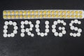 The word `drugs` is laid out of pills on a dark background with packets of pills Royalty Free Stock Photo