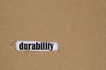 The word durability is written in a hole in the cardboard. The concept of durability