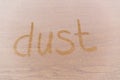 Word `Dust` written on dusty wooden surface