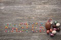 Word EASTER made of colorful sprinkles and chocolate eggs on wooden background