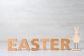 Word EASTER made of wooden letters and decorative bunny on table