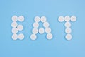 The word eat made from medical pills on a blue background. Drug addiction and overdose concept Royalty Free Stock Photo