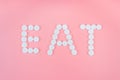 The word eat made from medical pills on a pink background. Drug addiction and overdose concept Royalty Free Stock Photo