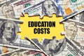 The word education costs surrounded by puzzle pieces with dollar bill money. Tuition budget or investment Royalty Free Stock Photo