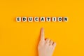 The word education written on wooden blocks with a child hand pointing to it Royalty Free Stock Photo