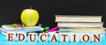 Word ` Education ` written by wooden cubes with school supplies on blue background against blackboard