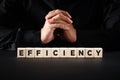 The word efficiency on wooden blocks with a businessman with clasped hands