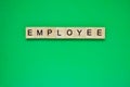 Word employee. Top view of wooden blocks with letters on green surface