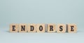 The word ENDORSE made from wooden cubes on blue background