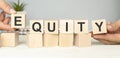 the word equity on wooden cubes, fair division of money, gray background top view, scattered cubes around