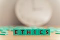 The word ETHICS made of small colorful cubes and many scrambled letters laying around on the table. Core Values