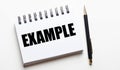 The word EXAMPLE is written in a white diary on a light background next to the pen. Motivational concept Royalty Free Stock Photo