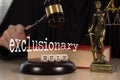 Word EXCLUSIONARY RULE composed of wooden dices. Wooden gavel and statue of Themis in the background