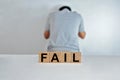 The word fail on wooden cubes, a person doing fail gesture on blur background, light wooden cubes signs, symbols signs